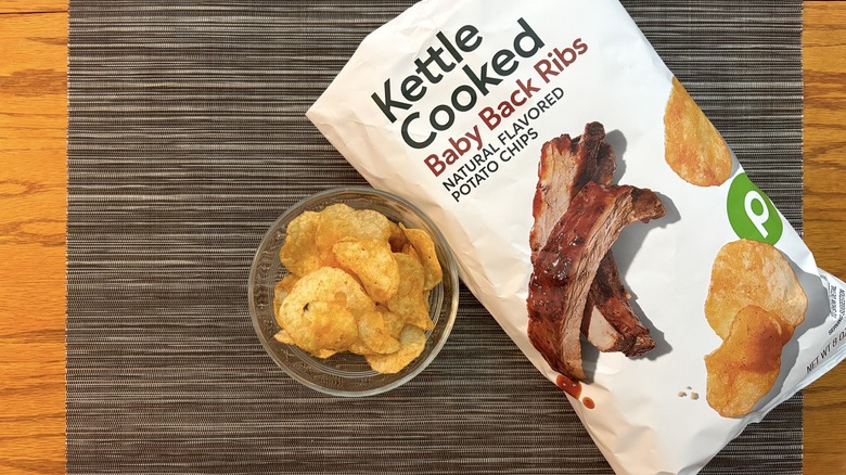Publix kettle cooked baby back ribs chips in bag and glass bowl on black placemat on wooden table in bag and glass bowl on black placemat on wooden table