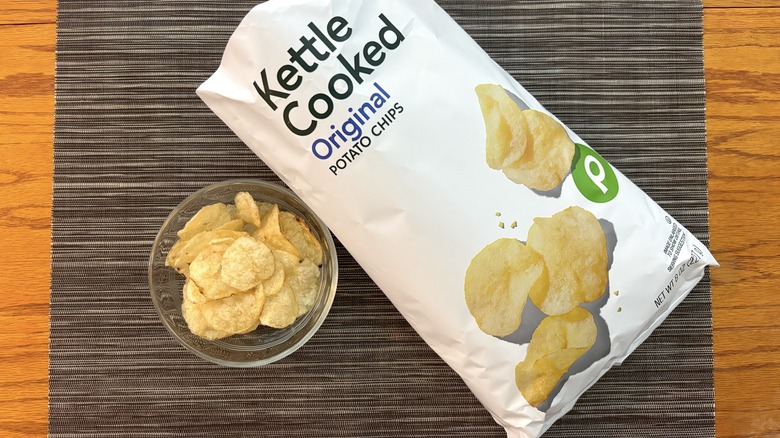 Publix kettle cooked original chips in bag and glass bowl on black placemat on wooden table in bag and glass bowl on black placemat on wooden table