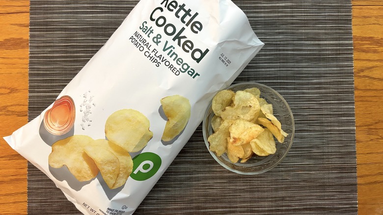 Publix kettle cooked salt & vinegar chips in bag and glass bowl on black placemat on wooden table in bag and glass bowl on black placemat on wooden table