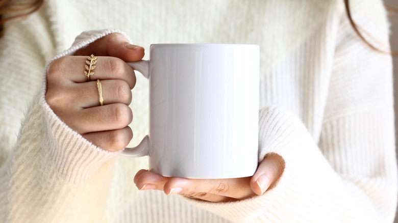 Person holding white ceramic mug