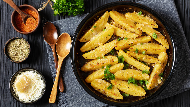 Pot of roasted lemon potatoes with Parmesan cheese and wooden spoons