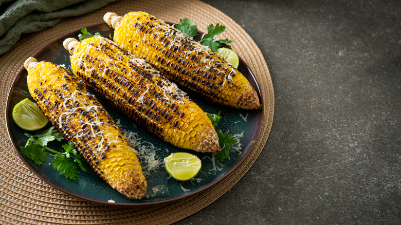 Three ears of grilled corn on the cob with cheese and lime