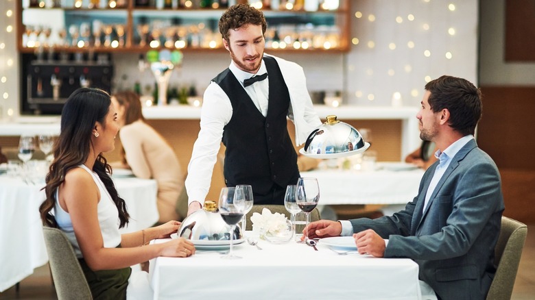 Waiter serving couple