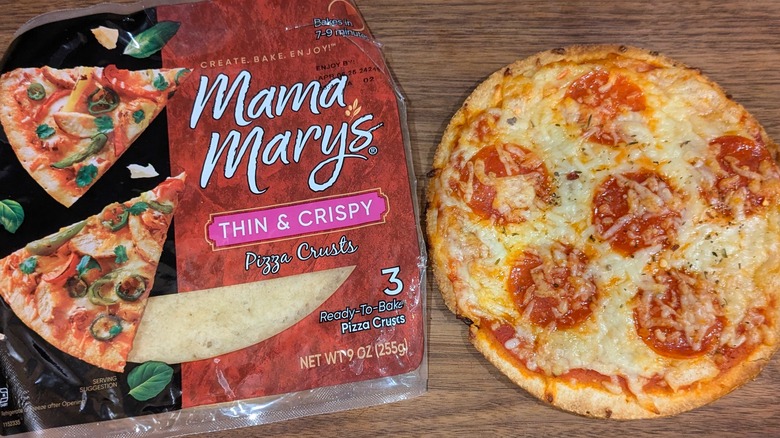 Small bag of Mama Mary's thin pizza crusts next to mini pepperoni pizza on wood board