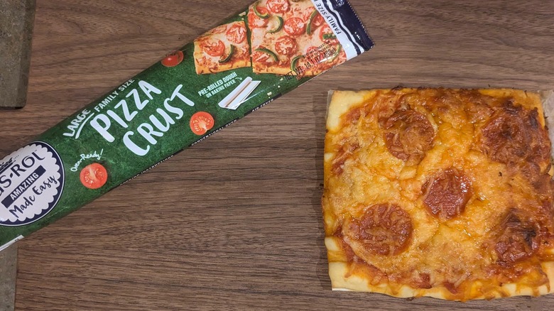 Long, green plastic bag with logo for pizza crust next to square pepperoni pizza on wood board