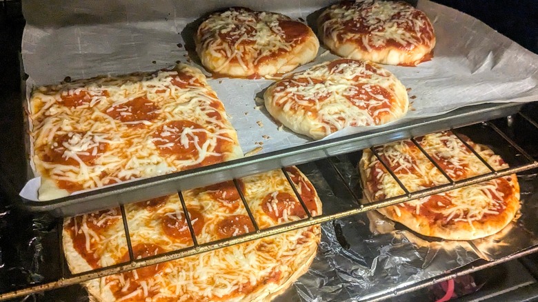 6 pizzas of various shapes and sizes baking in oven