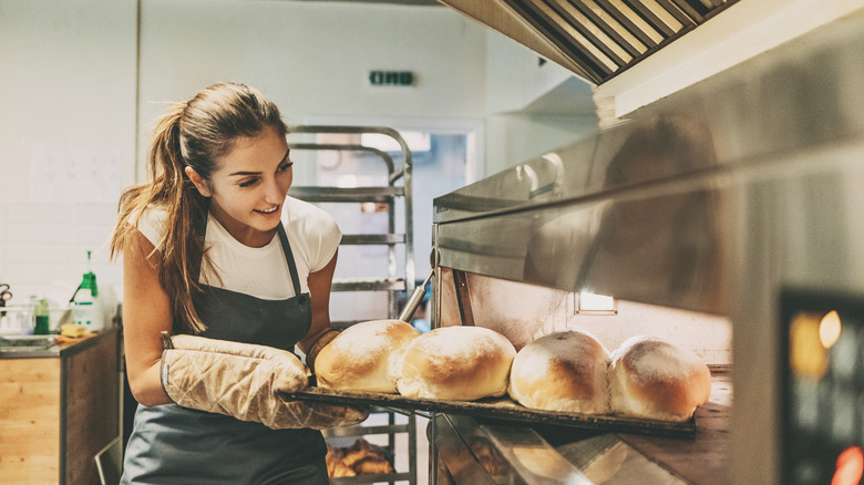 pulling bread out of oven