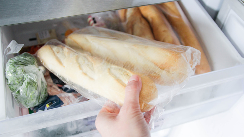 Hand taking bag of baguette out of a opened freezer