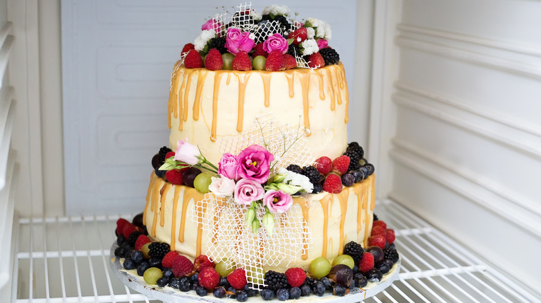 A whole wedding cake with flowers inside of fridge