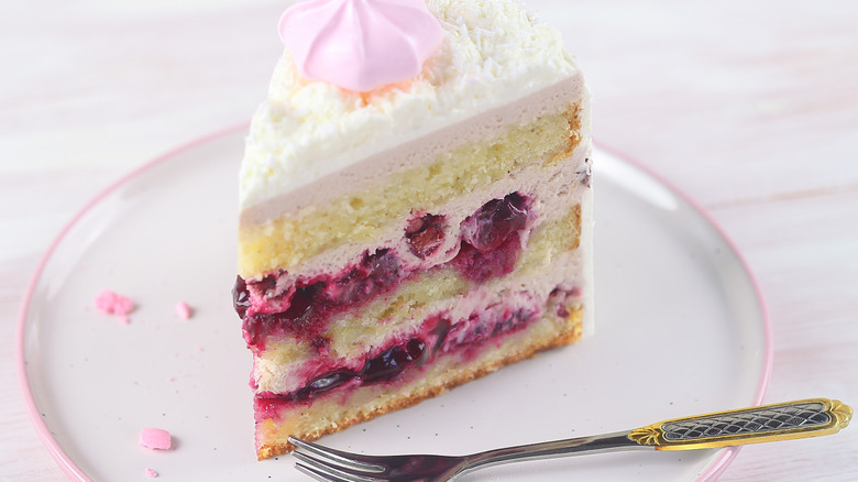 A slice of pink cake on plate with a fork