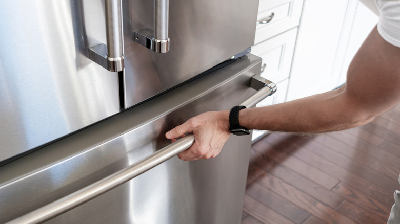 Person's hand grabbing the handle of freezer drawer