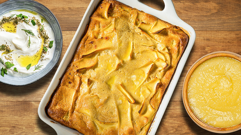 Noodle kugel in pan surrounded by homemade sauces