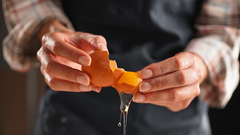 person separating egg yolk with shell