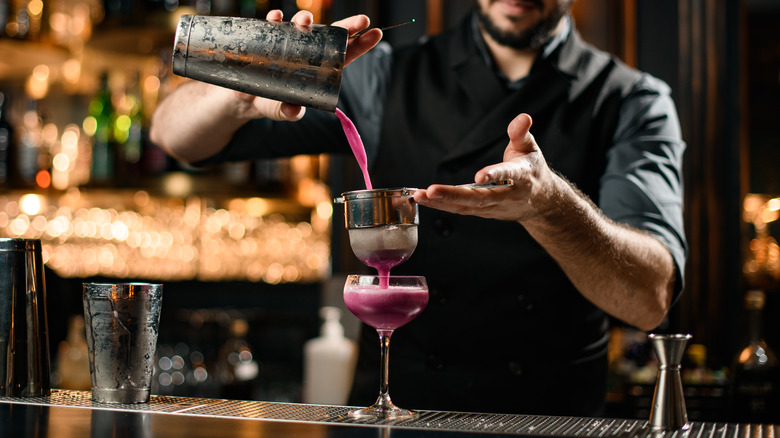 bartender double-straining a cocktail