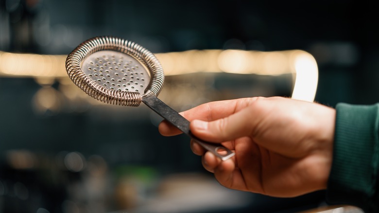 person holding a hawthorne strainer