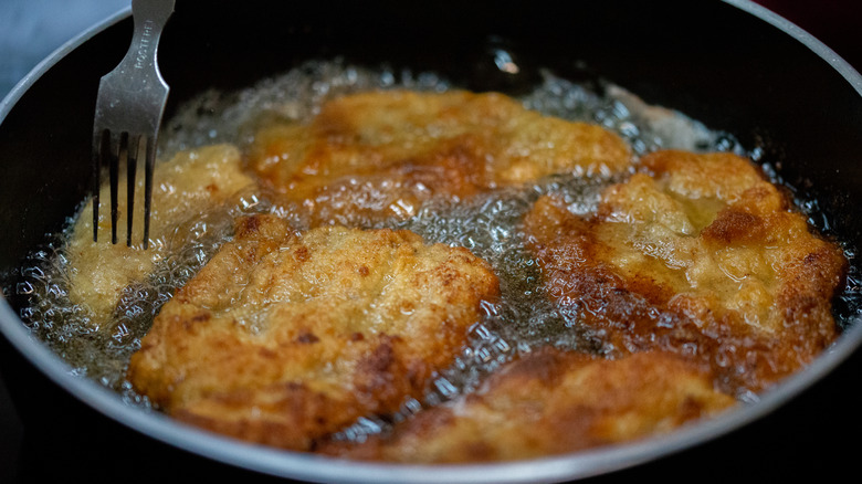 Five vegan fried chicken pieces in a pan with oil