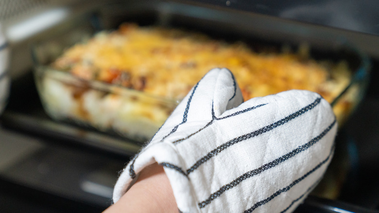 Oven mitt reaching for dish