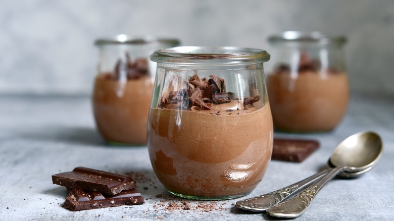 Containers of chocolate mousse with spoons nearby