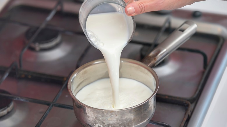 Pouring milk into pot on stove