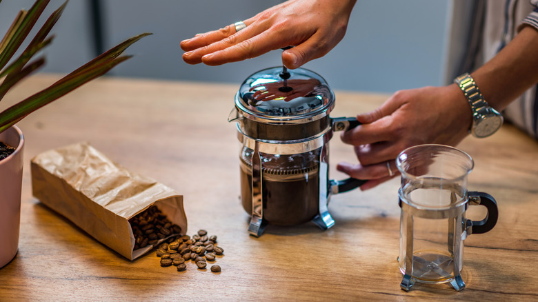 Person making French press coffee