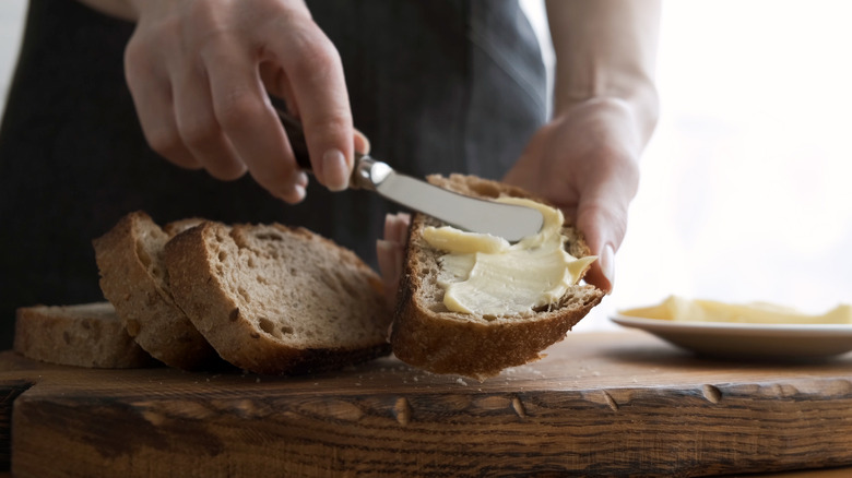 person buttering slices of bread