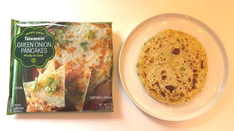 Package of Trader Joe's Green Onion Pancakes next to cooked green onion pancake on white plate