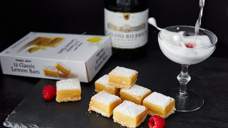 Trader Joe's Lemon Bars next to cocktail and raspberries on black surface