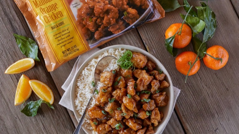 Trader Joe's Mandarin Orange Chicken bag next to white bowl of rice and chicken