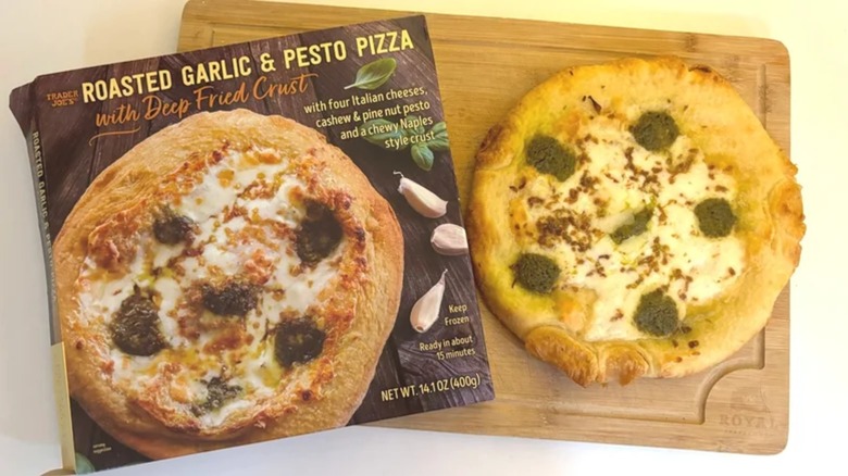 Trader Joe's Roasted Garlic Pesto Pizza box next to pizza on cutting board