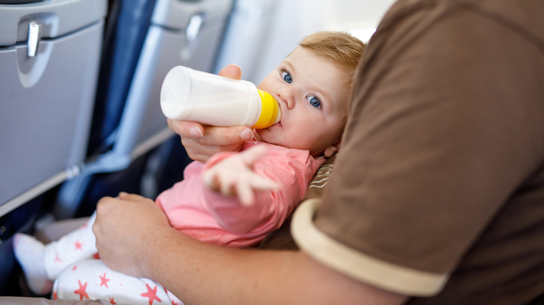 Baby drinking milk from a bottle in a plane