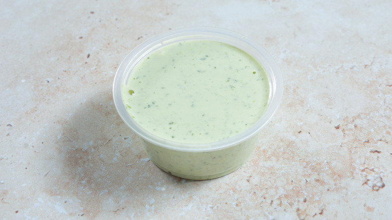 Plastic cup of green salad dressing