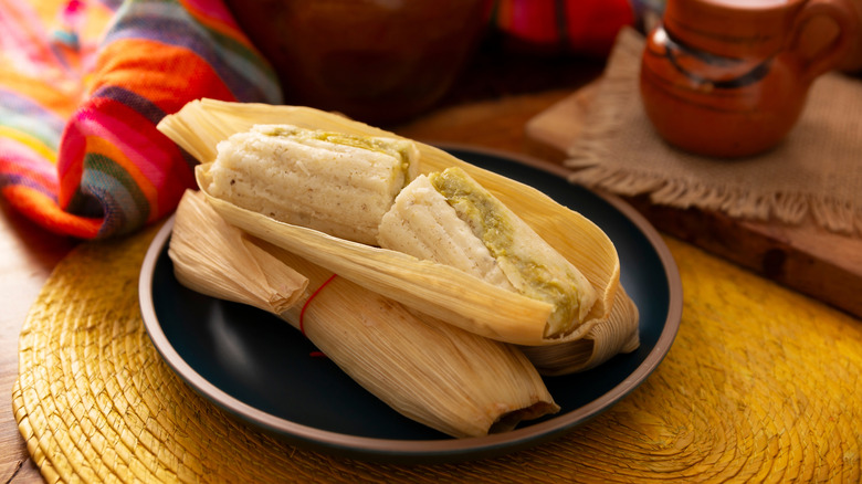 Two tamales on plate with yellow woven place mat