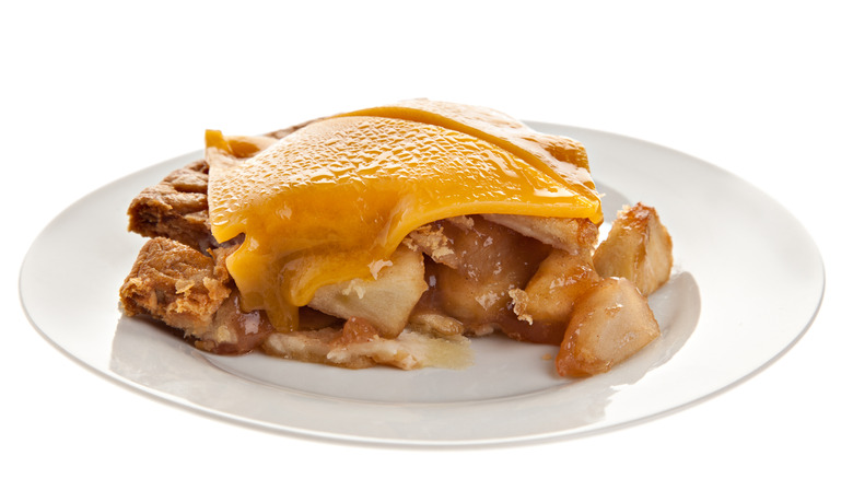 Plate of apple pie with cheese on top on white background