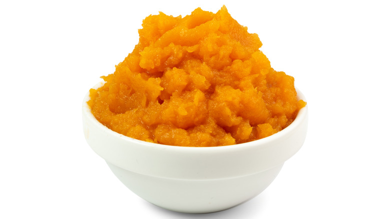 Whipped sweet potatoes are piled into a white bowl.