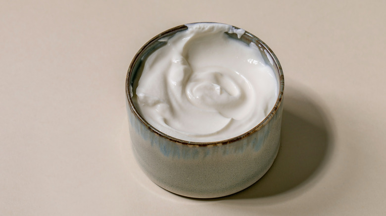 A bowl of sour cream sits on a white background.