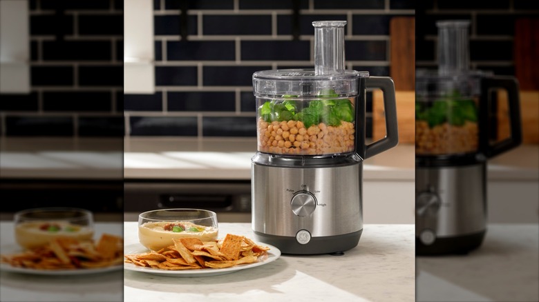 GE 12-Cup Food Processor sitting on kitchen counter containing ingredients to make hummus