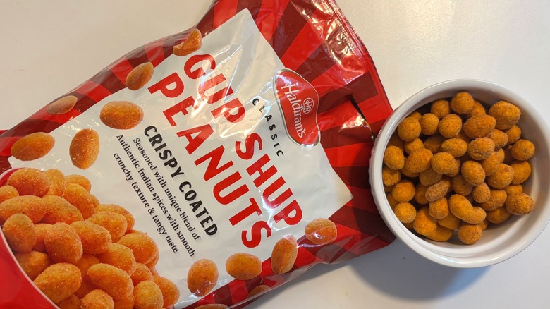 Bowl of Gup Shup peanuts next to red Gup Shup bag on white table