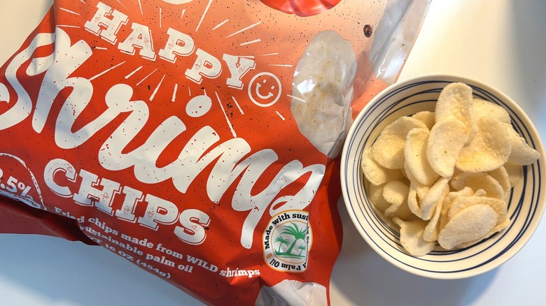 Bowl of Happy Shrimp Chips next to orange bag of shrimp chips on white table