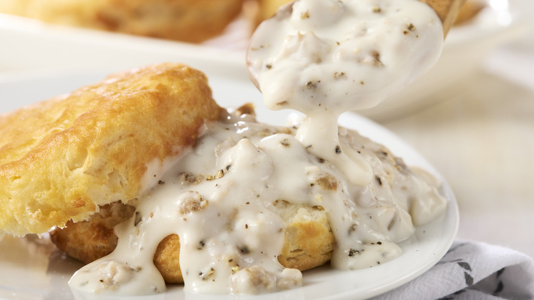 Spoon pouring gravy on biscuit