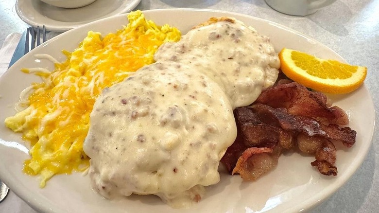 Biscuits and gravy with bacon, eggs, and orange