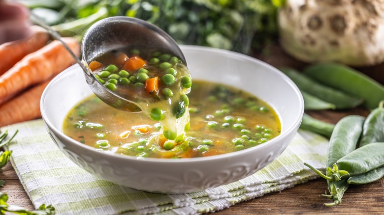 Ladling vegetable soup in bowl