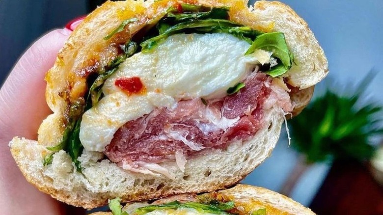 Person holding prosciutto sandwich