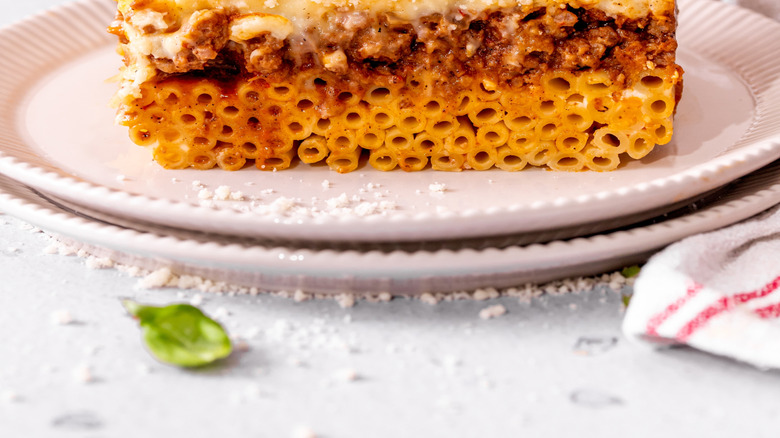 Creamy comfort casserole dish called Pastitsio from Greece, served on a plate with fresh basil leaves