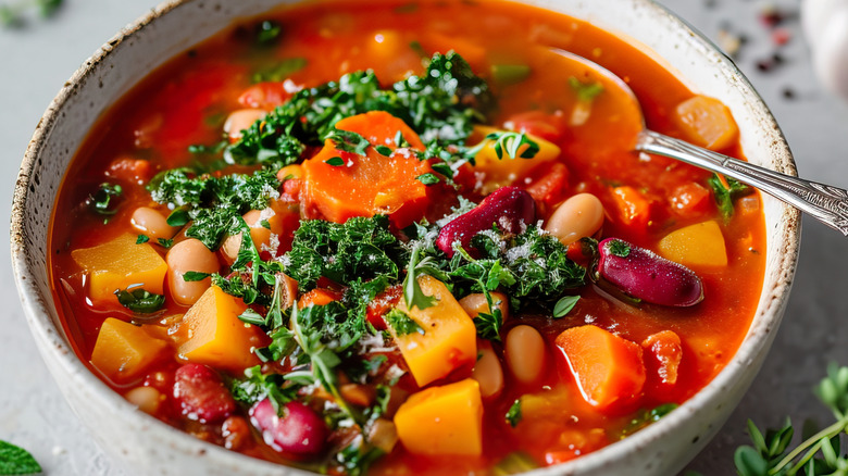 Minestrone soup in a bowl with vegetables and herbs