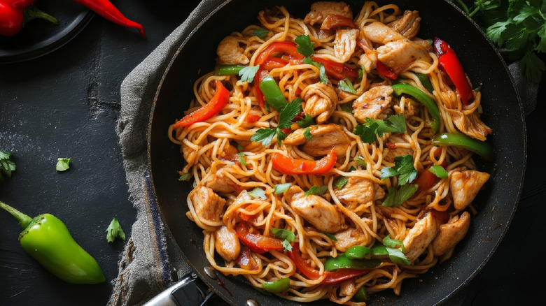 chicken and noodles stir-fry in a black wok