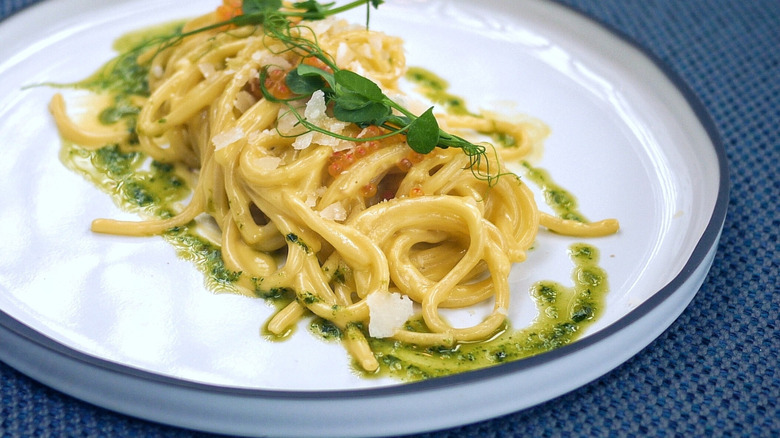 bucatini with oil based herb sauce on white plate