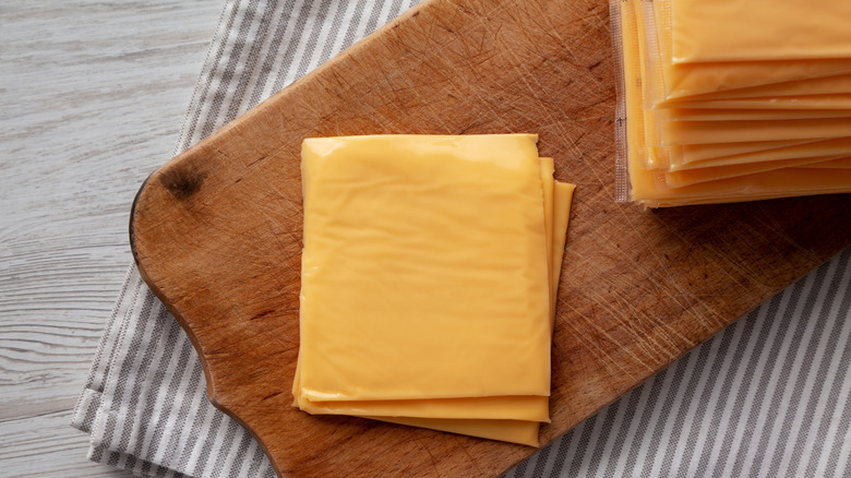 Yellow sliced American cheese on a cutting board