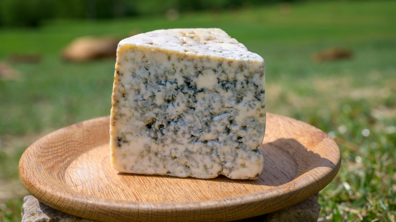 Large wedge of Cabrales blue cheese on wooden plate