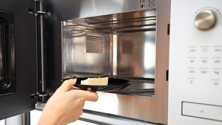 Hand placing butter into microwave