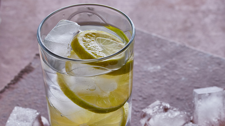 Cocktail of the 1920's gin Rickey served in a tall glass,there is melting ice in the image,shot on a tiled surface.